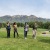 people walking in a park with a mountain range behind them