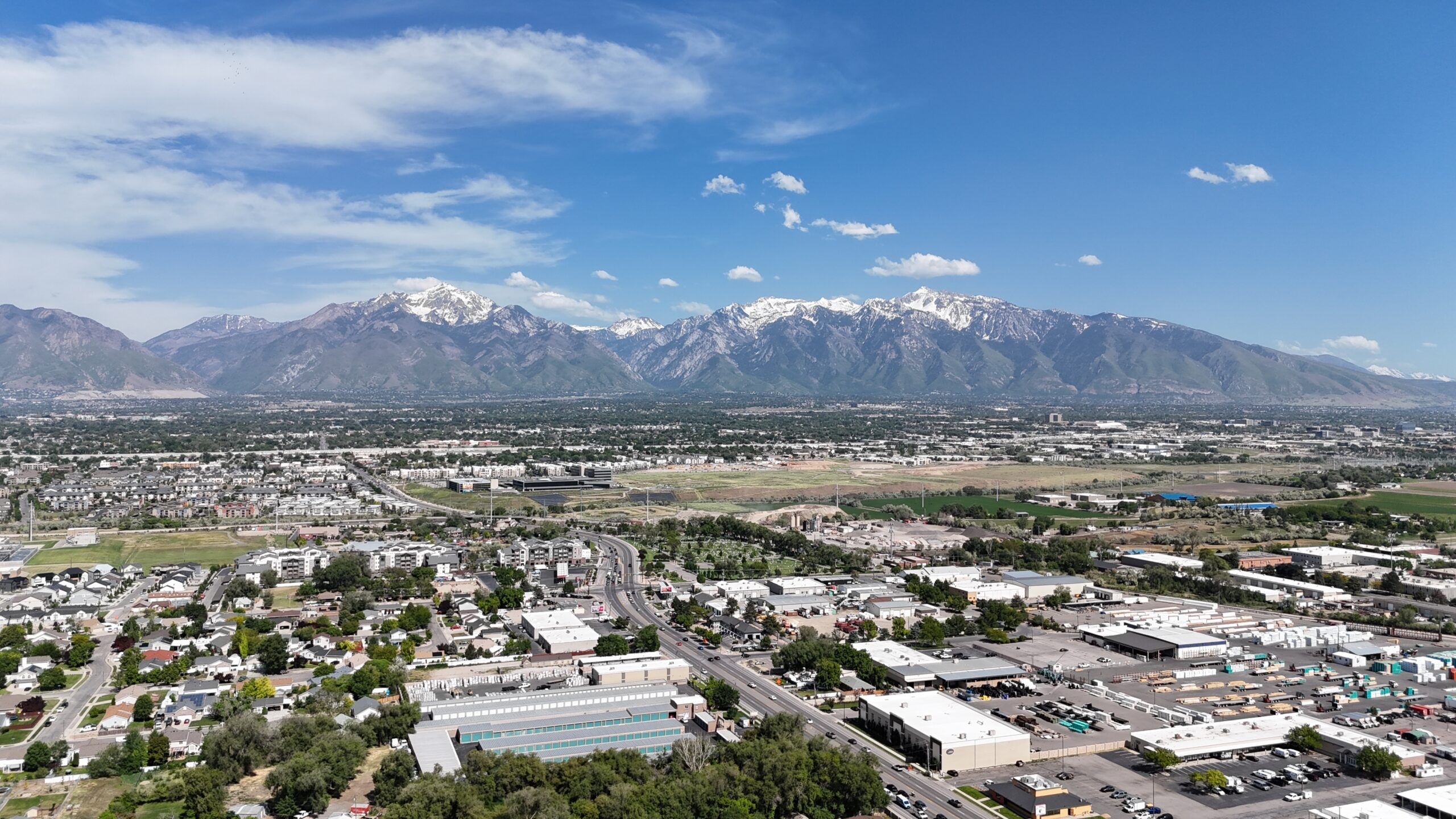 Montaire Student Living Apartments Aerial view of a city with snow-capped mountains in the background under a blue sky.