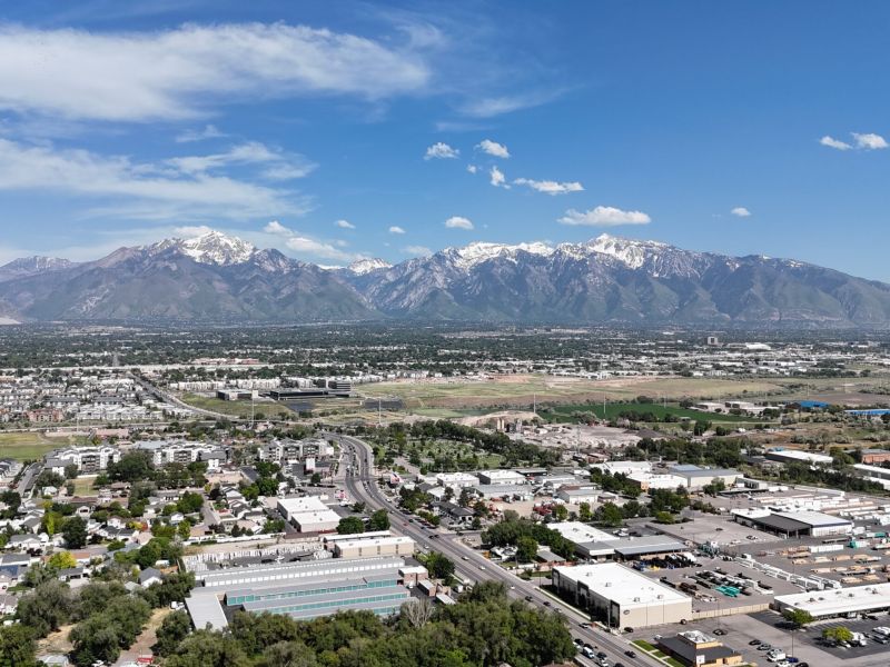 Montaire Student Living Apartments Aerial view of a city with snow-capped mountains in the background under a blue sky.