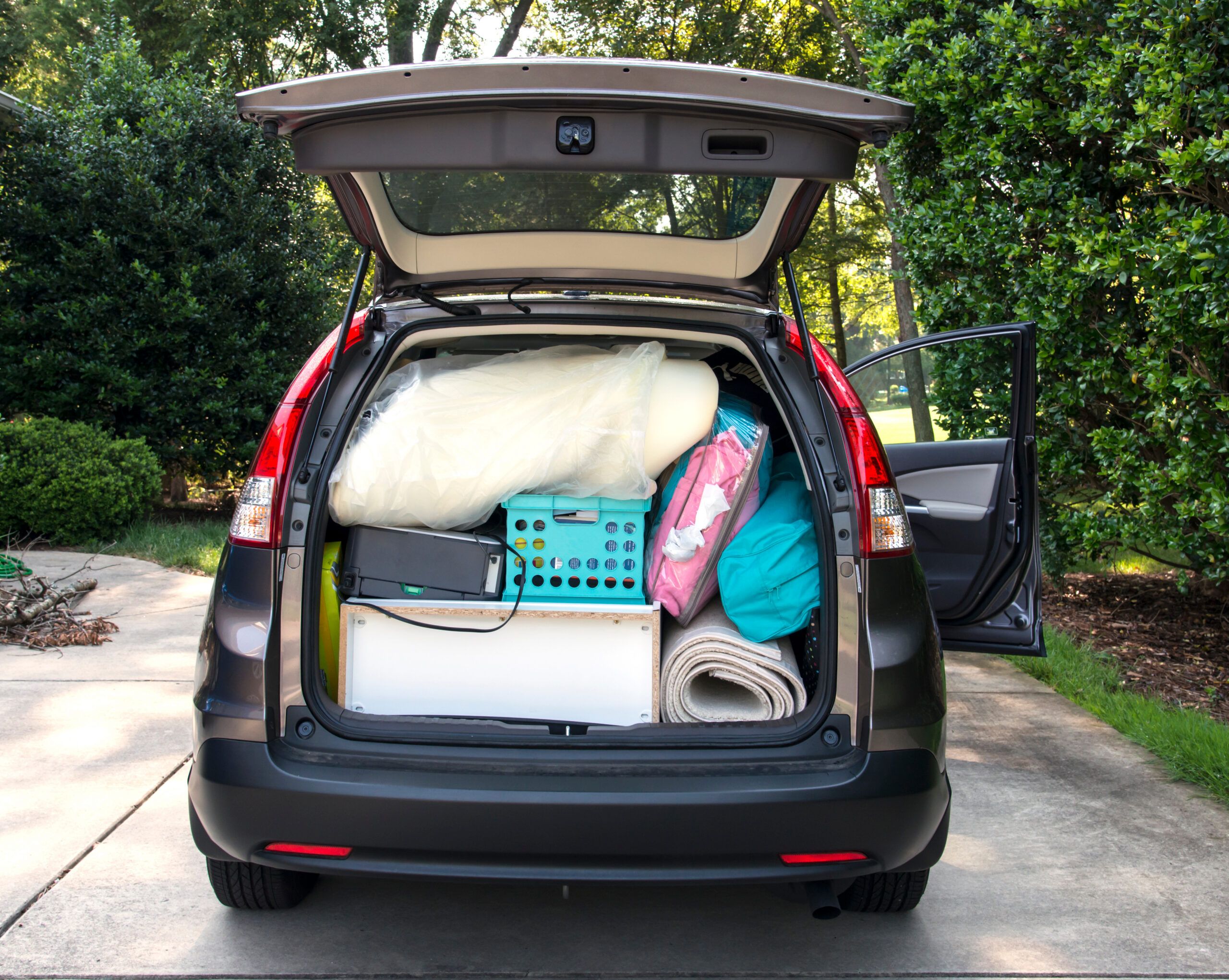 Montaire Student Living Apartments Car trunk packed with boxes, bags, and household items, ready for moving, with the tailgate open.