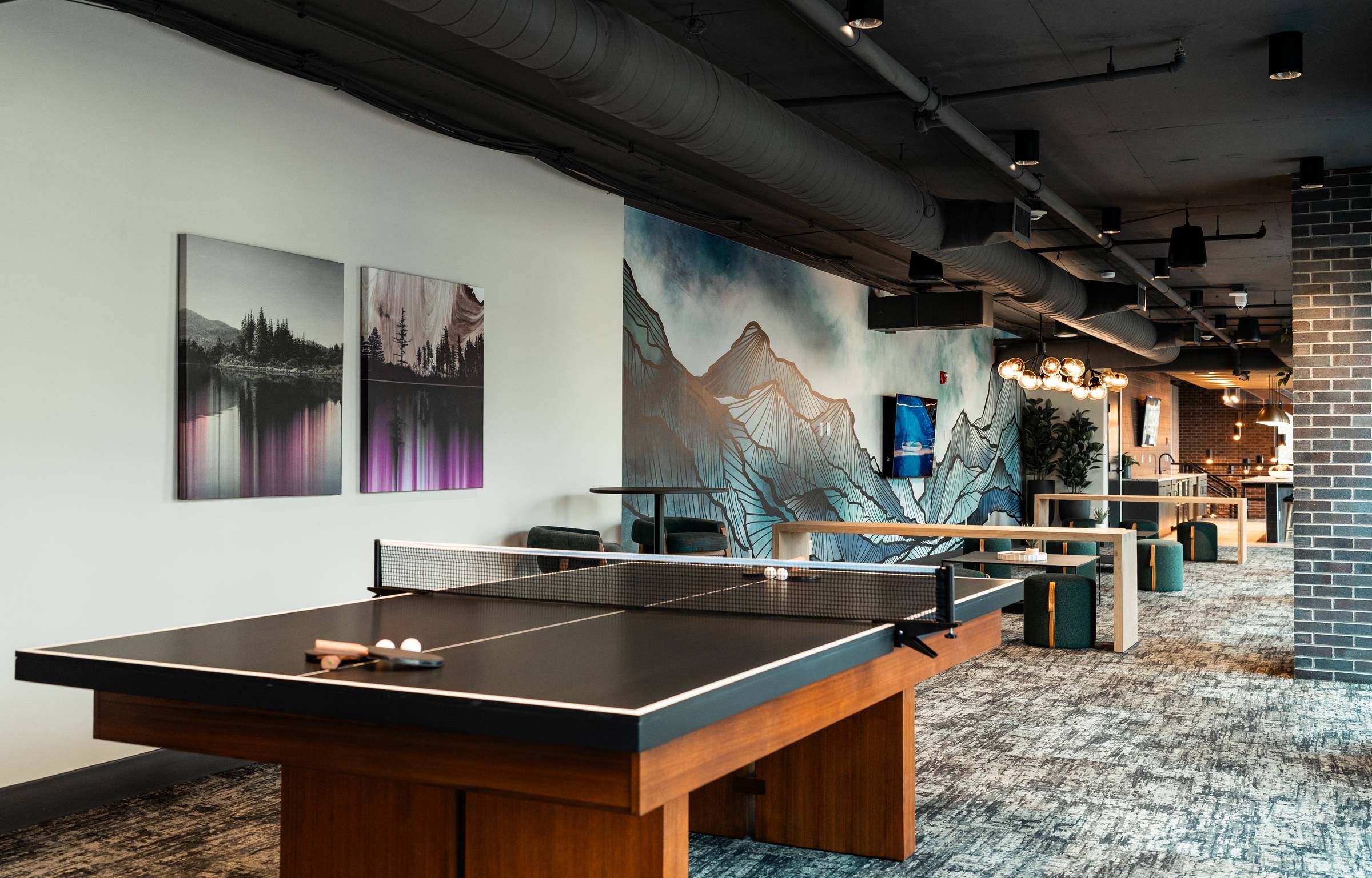 Montaire Student Living Apartments Modern lounge with a ping pong table, art on the walls, and mountain mural in the background.