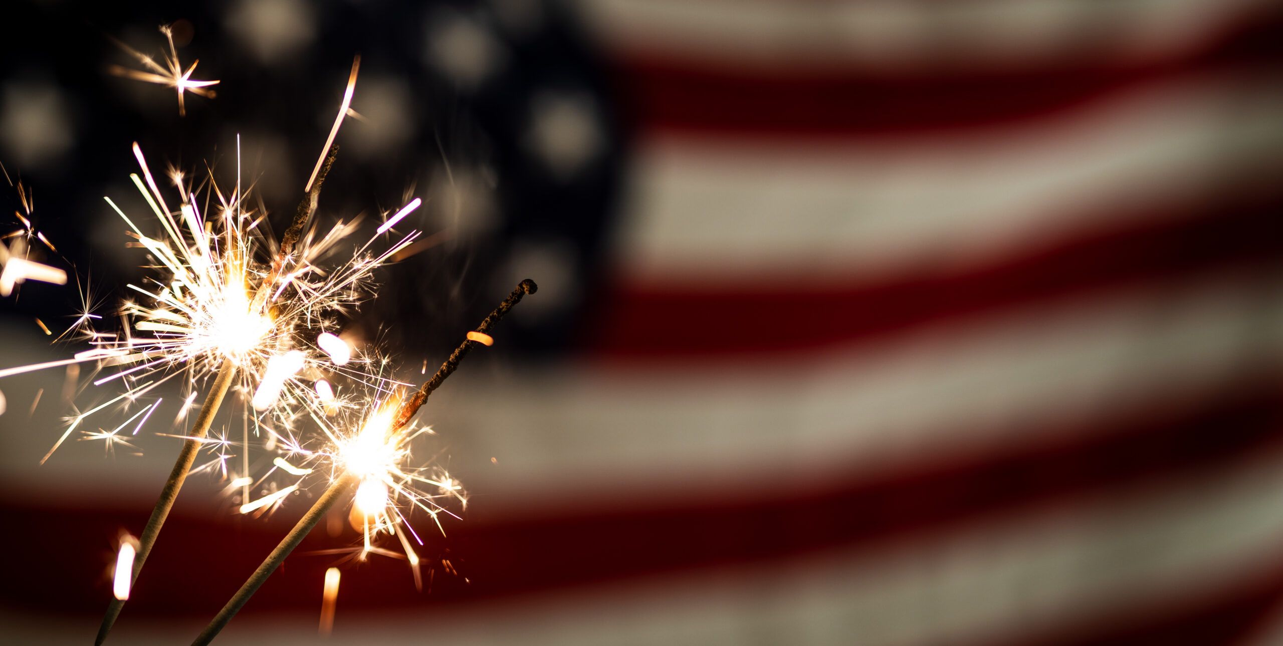 Montaire Student Living Apartments Sparklers burning in front of a blurred American flag background.