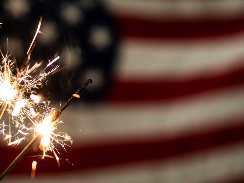 Montaire Student Living Apartments Sparklers burning in front of a blurred American flag background.