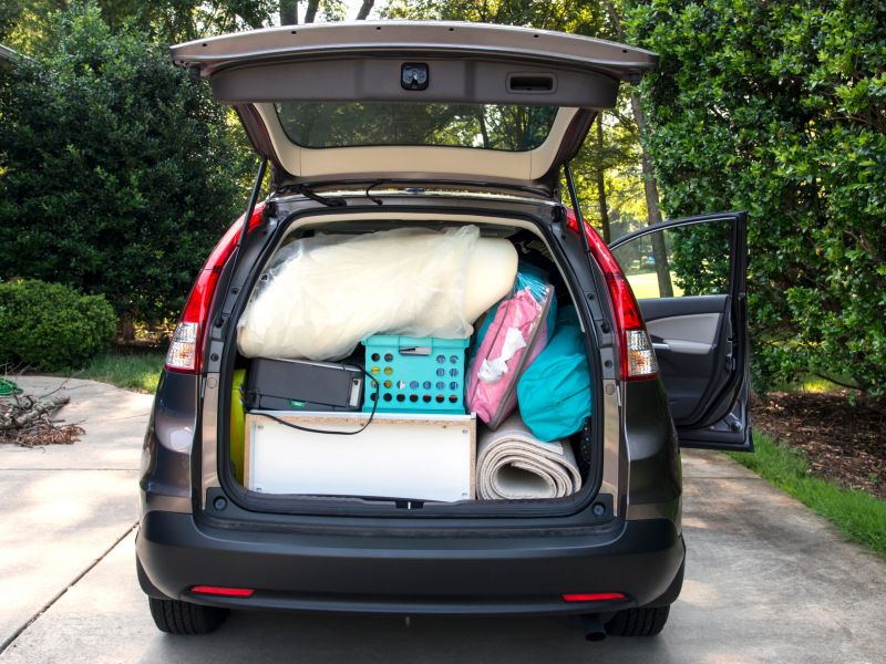 Montaire Student Living Apartments Car trunk packed with boxes, bags, and household items, ready for moving, with the tailgate open.