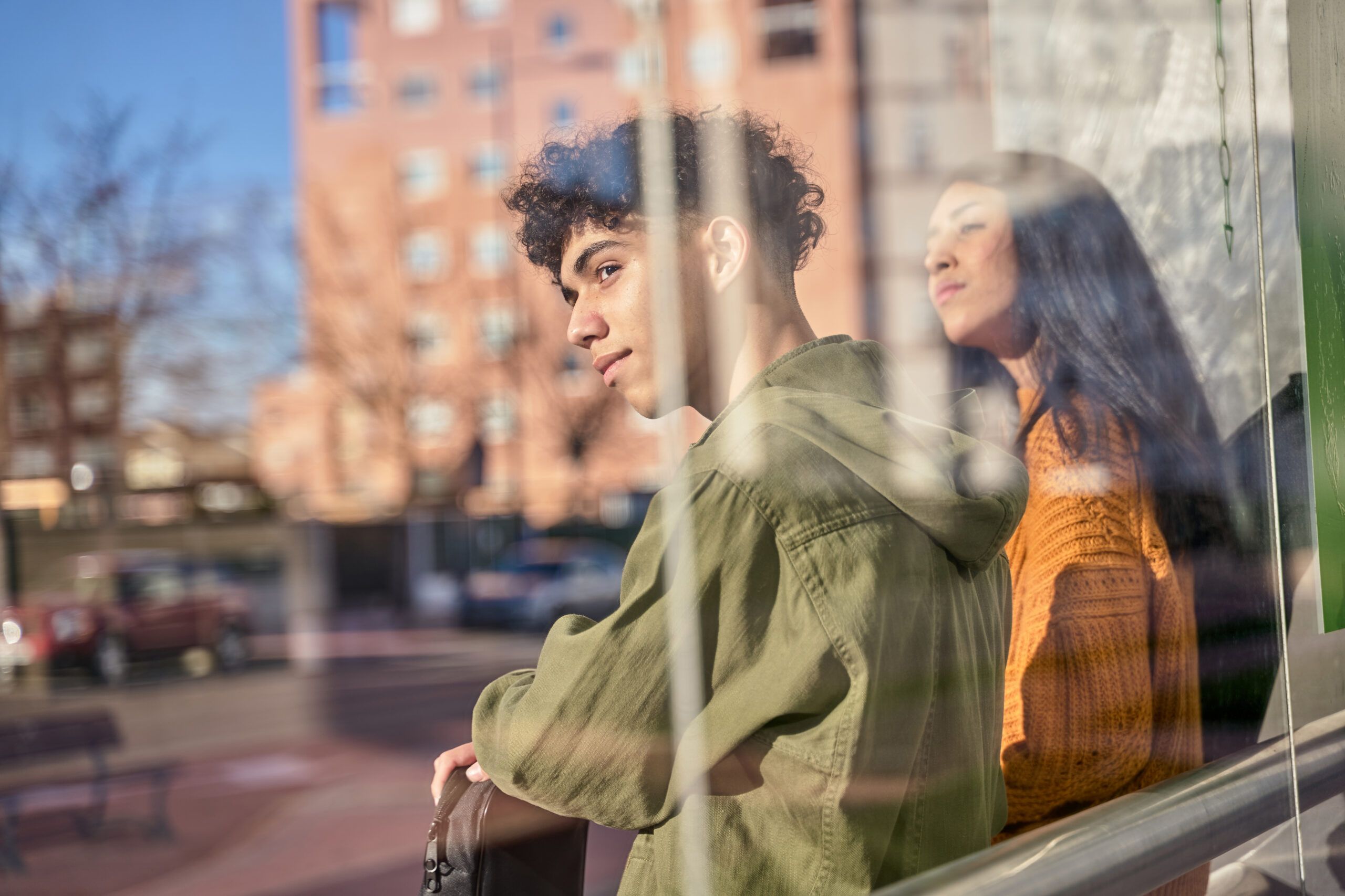 Montaire Student Living Apartments Two people stand by a window, looking outside with thoughtful expressions; city buildings are visible.